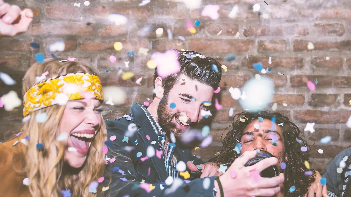 Friends making big party in the night. Four people throwing confetti and drinking champagne