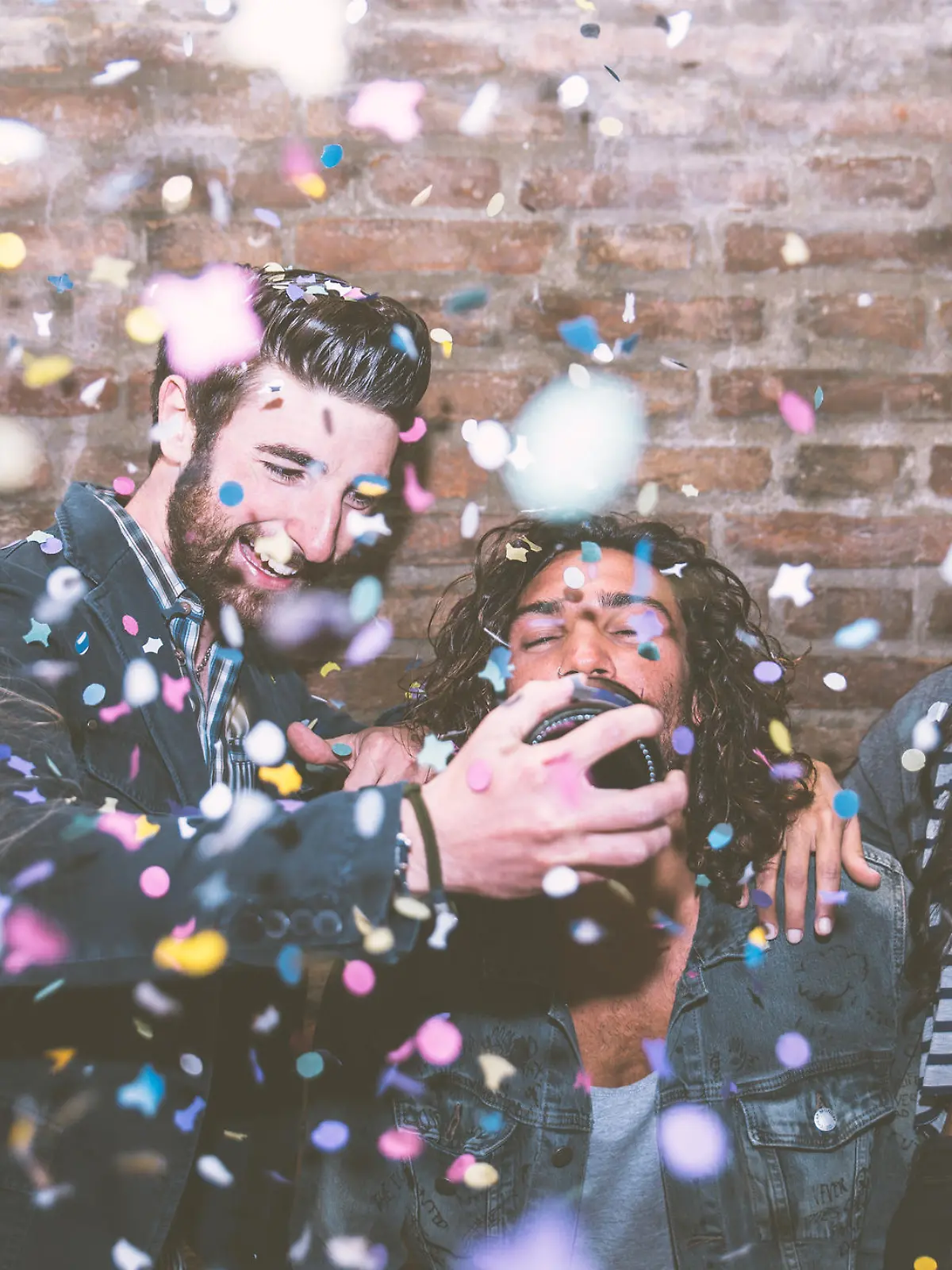 Friends making big party in the night. Four people throwing confetti and drinking champagne