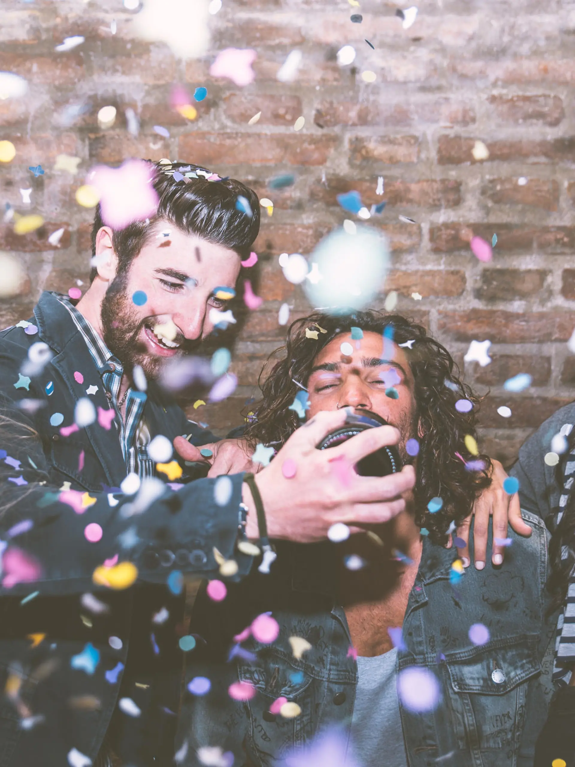 Friends making big party in the night. Four people throwing confetti and drinking champagne