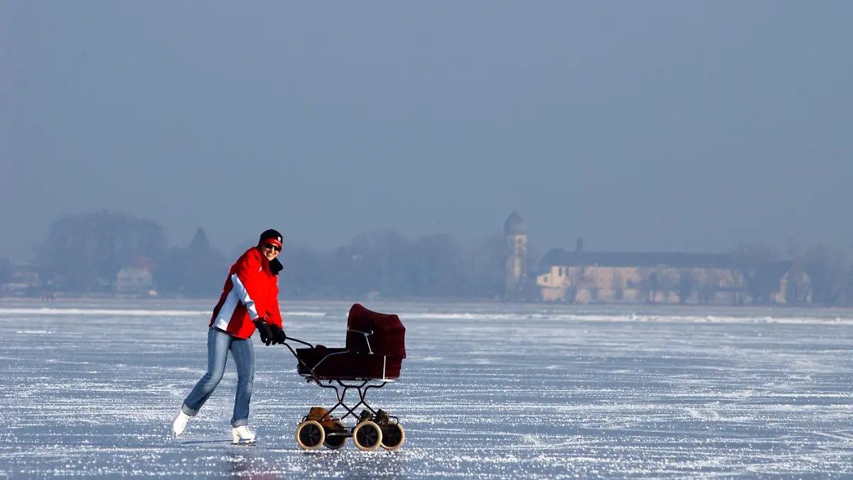 Den zugefrorenen Chiemsee bei Rimsting (Oberbayern) nutzt am Donnerstag (08.01.2009) diese Frau, um mit Schlittschuhen und Kinderwagen den Winter zu genießen. Im Hintergrund ist das Kloster Frauenchiemsee der Benediktinerinnenabtei Frauenwörth zu sehen. Auch wenn in Bayern keine rekordverdächtigen Minusgrade herrschen, steigen die Temperaturen auch tagsüber nicht über die Null-Grad-Marke. Foto: Ken Liu dpa/lby +++(c) dpa - Bildfunk+++