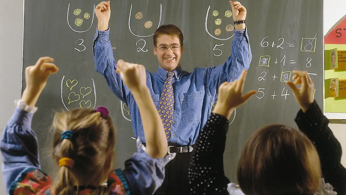 Ein Lehrer zeigt im Mathematikunterricht gemeinsam mit seinen Schülern auf.