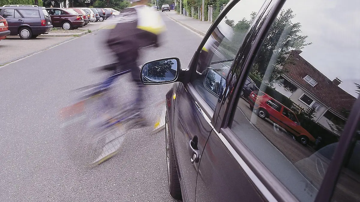 Ein Kind fährt mit einem Fahrrad vor ein Auto.