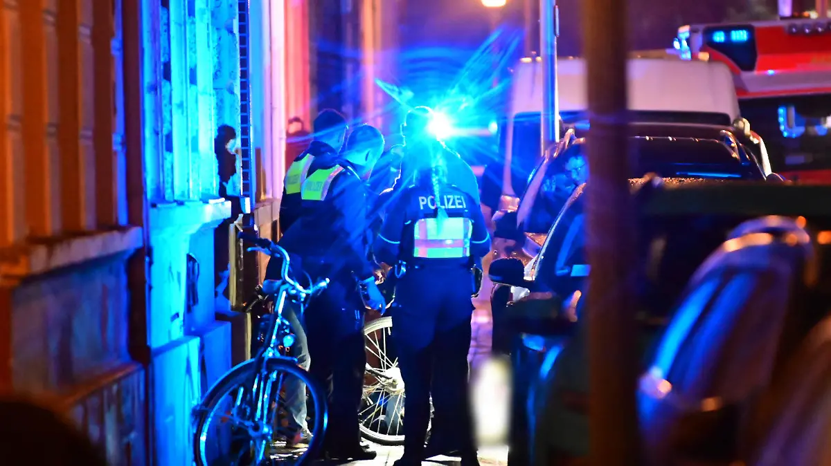 28.11.2022, Nordrhein-Westfalen, Krefeld: Polizisten stehen auf einem Geweg neben dem Toten. In der Krefelder Innenstadt ist am Montagabend ein Mann auf offener Straße erschossen worden. «Es gab eine Schussabgabe auf der Garnstraße. Eine Person ist verstorben», sagte ein Sprecher der Polizei auf Anfrage der Deutschen Presse-Agentur. Foto: Alex Forstreuter/dpa +++ dpa-Bildfunk +++