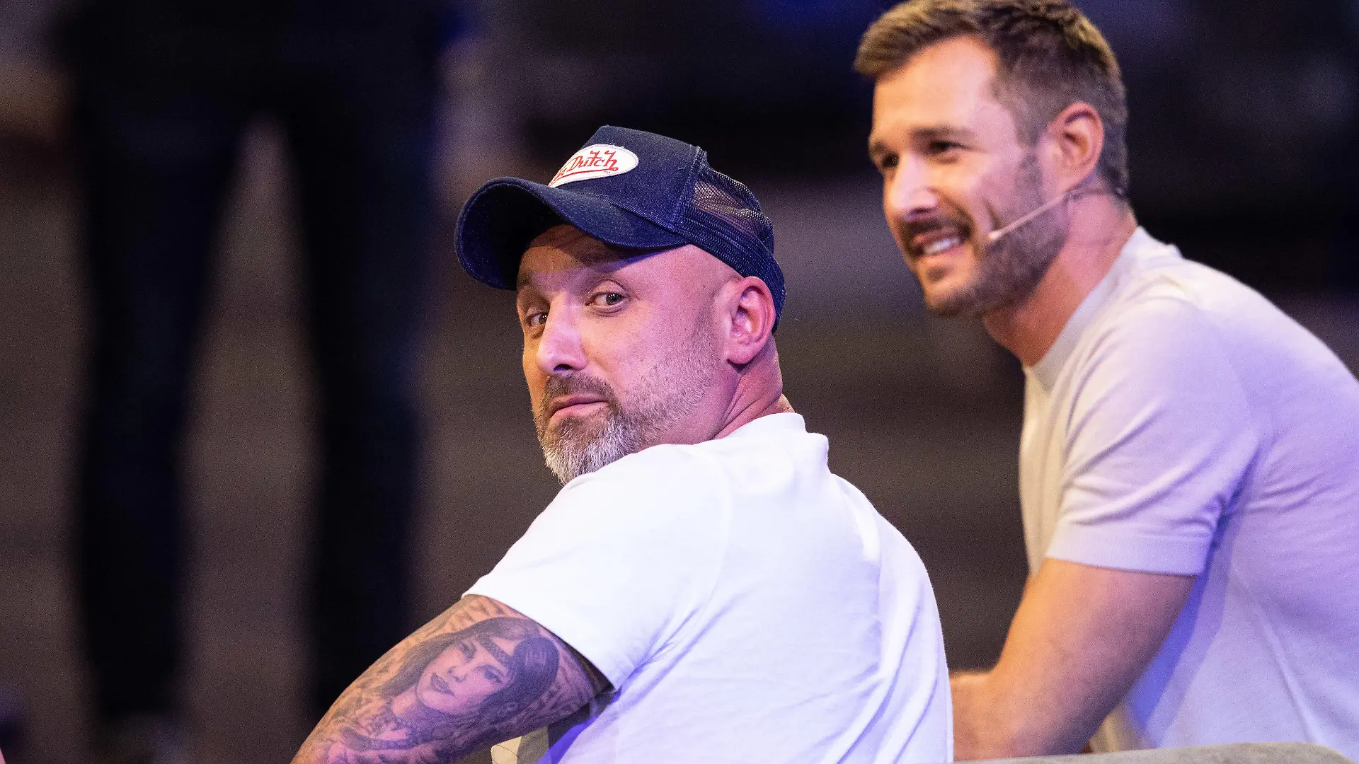 09.08.2019, Nordrhein-Westfalen, Köln: Zlatko (l) sitzt bei der Auftaktshow zur neuen Staffel der Sat.1 Realityshow "Promi Big Brother" auf der Bühne neben Moderator Jochen Schropp. (zu dpa "Überlänge, TV-Comeback und Abschiedstränen bei «Promi Big Brother»") Foto: Marcel Kusch/dpa +++ dpa-Bildfunk +++