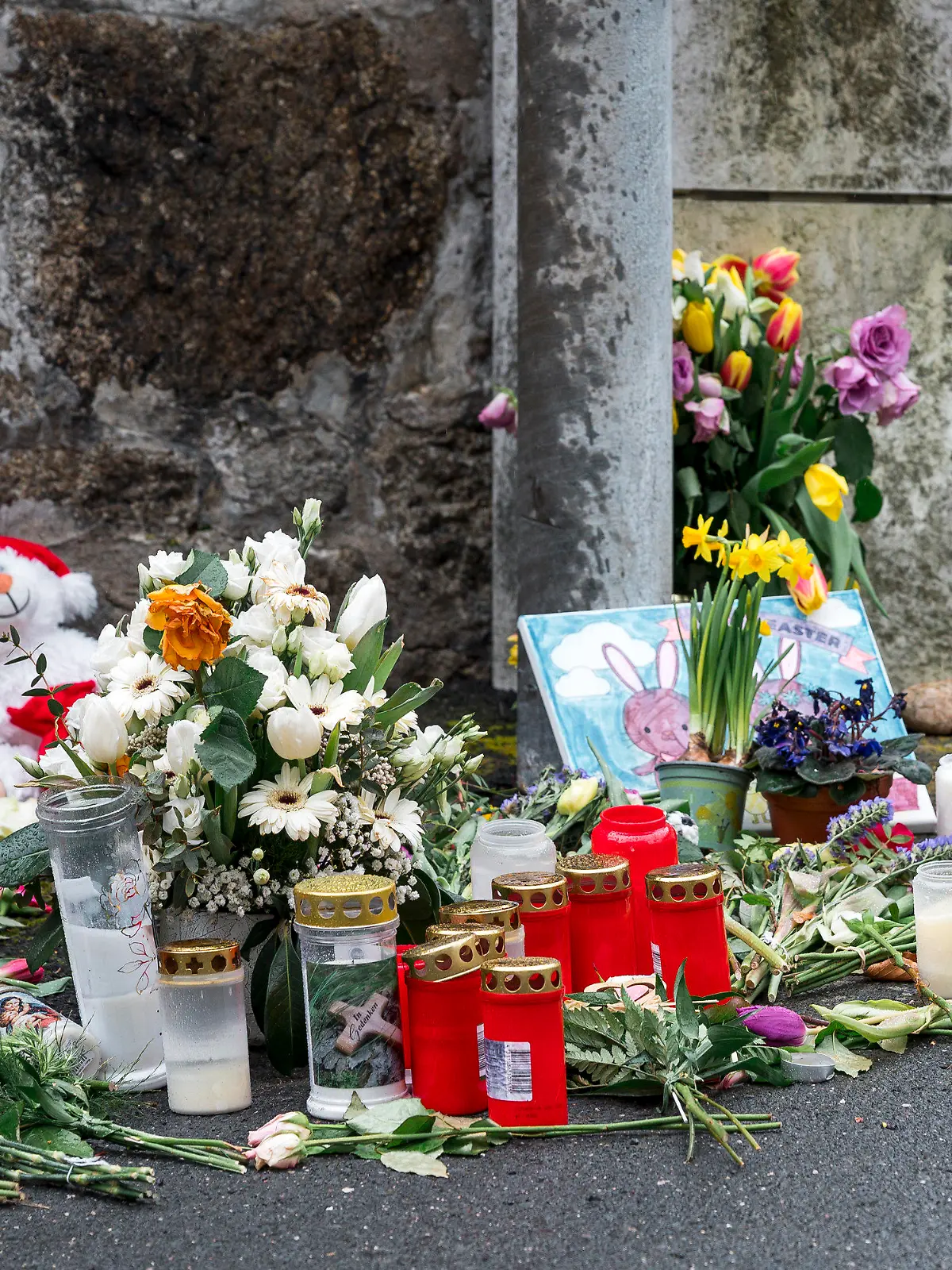 ARCHIV - 12.04.2023, Bayern, Wunsiedel: An einer Mauer vor dem Kinder- und Jugendhilfezentrum, in dem eine Zehnjährige tot aufgefunden wurde, liegen Blumen, Kuscheltiere und Kerzen. (zu dpa: «Totes Mädchen in Wunsiedel - Mann wegen Vergewaltigung angeklagt») Foto: Daniel Vogl/dpa +++ dpa-Bildfunk +++