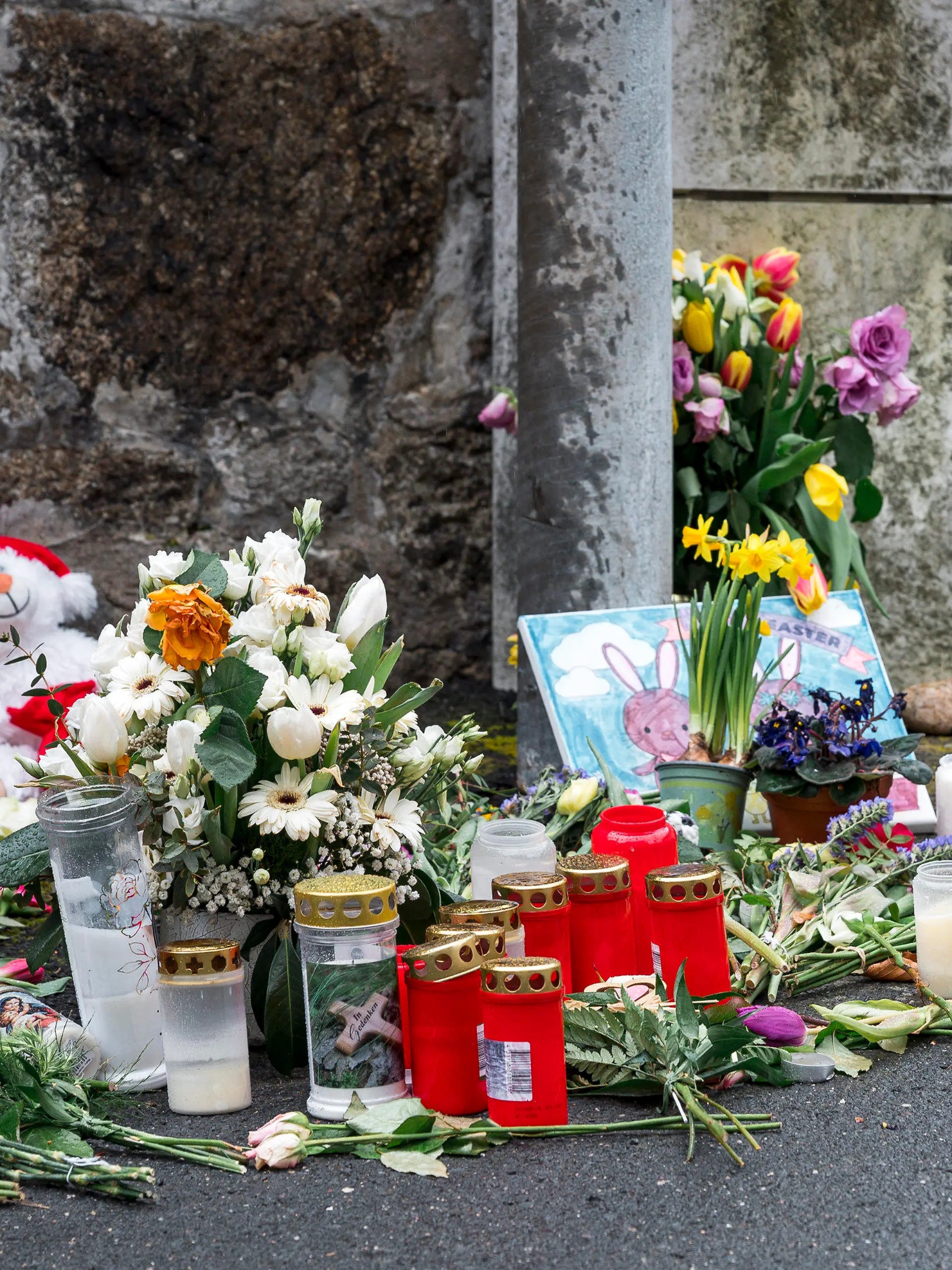 ARCHIV - 12.04.2023, Bayern, Wunsiedel: An einer Mauer vor dem Kinder- und Jugendhilfezentrum, in dem eine Zehnjährige tot aufgefunden wurde, liegen Blumen, Kuscheltiere und Kerzen. (zu dpa: «Totes Mädchen in Wunsiedel - Mann wegen Vergewaltigung angeklagt») Foto: Daniel Vogl/dpa +++ dpa-Bildfunk +++