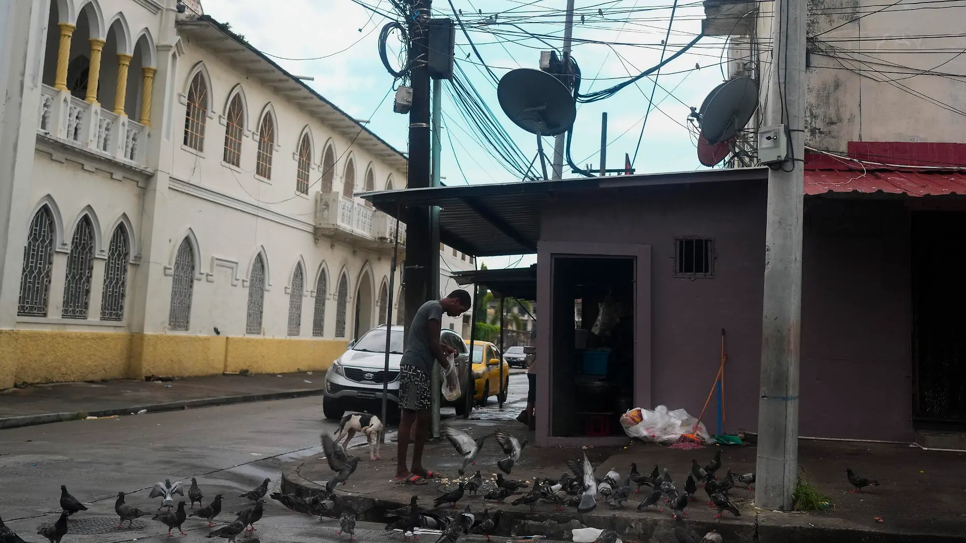 A man feeds pigeons on a street where Gilberto Hernandez, a member of Panama's national soccer team, was shot and killed in Colon, Panama, Monday, Sept. 4, 2023. Hernández was the second member of the national team killed in Colon in the past six years. (AP Photo/Arnulfo Franco)