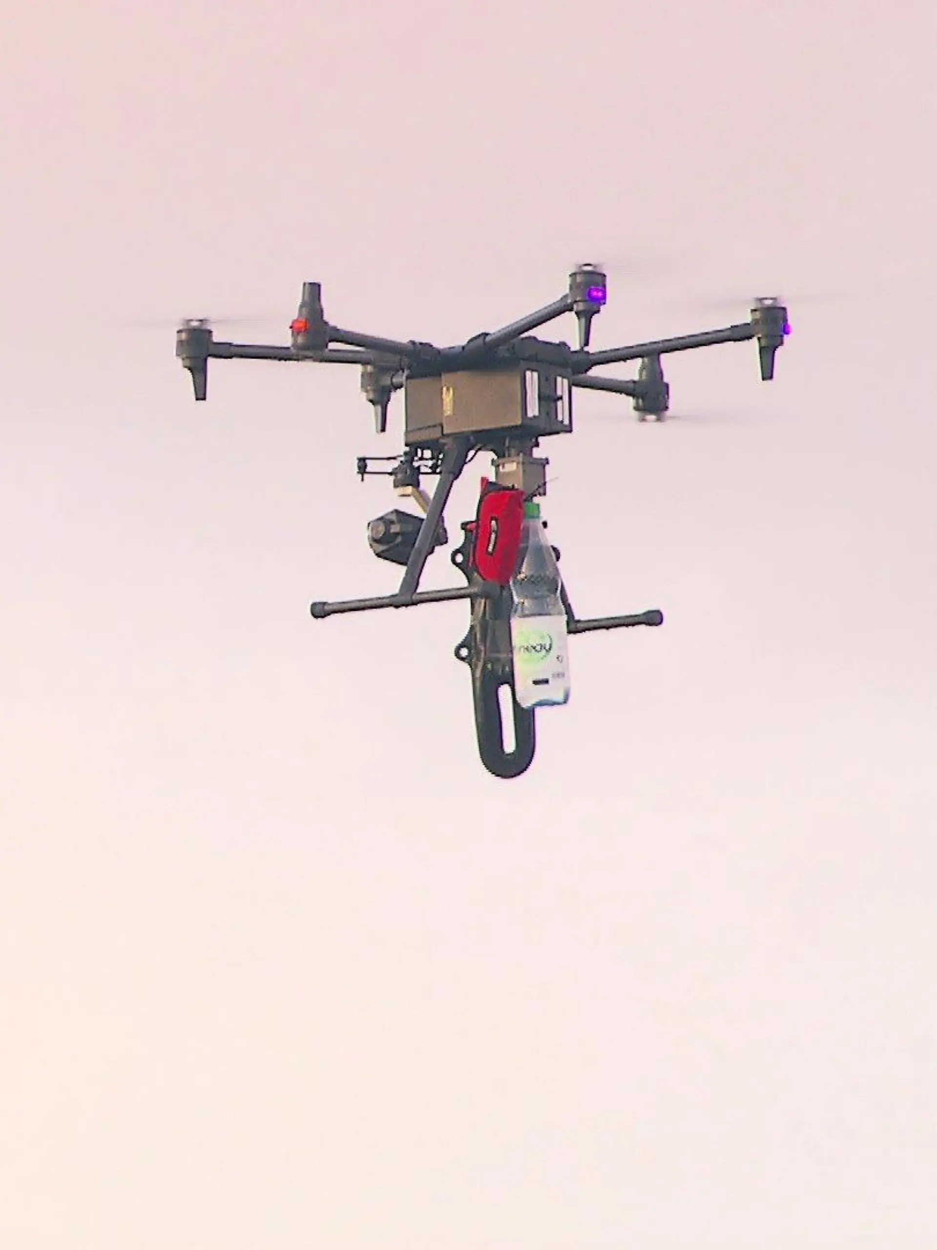 Eine Drohne transportiert eine Wasserflasche.