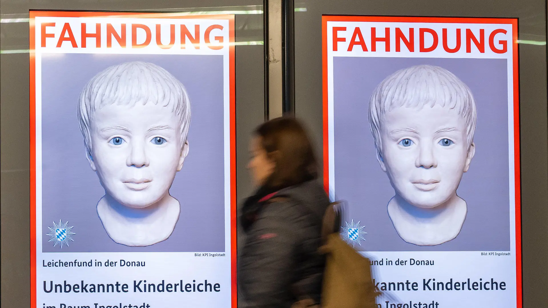 ARCHIV - 05.01.2023, Bayern, München: Eine Frau geht am Ostbahnhof an einem digitalen Fahndungsplakat vorbei. Vor mehr als einem Jahr entdeckt ein Kanufahrer eine Kinderleiche in der Donau. Wer der Junge war und was hinter der Tat steckt, ist bis heute nicht geklärt. Nach einem Aufruf der Polizeibehörde Interpol gibt es nun Hinweise. (zu dpa: «Interpol erhält nach Aufruf etliche Hinweise zu totem Jungen in Donau») Foto: Peter Kneffel/dpa +++ dpa-Bildfunk +++