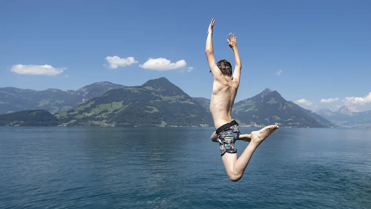 24.06.2020, Schweiz, Beckenried: Ein Junge springt bei Sonnenschein in den Vierwaldstättersee. Foto: Urs Flueeler/KEYSTONE/dpa +++ dpa-Bildfunk +++