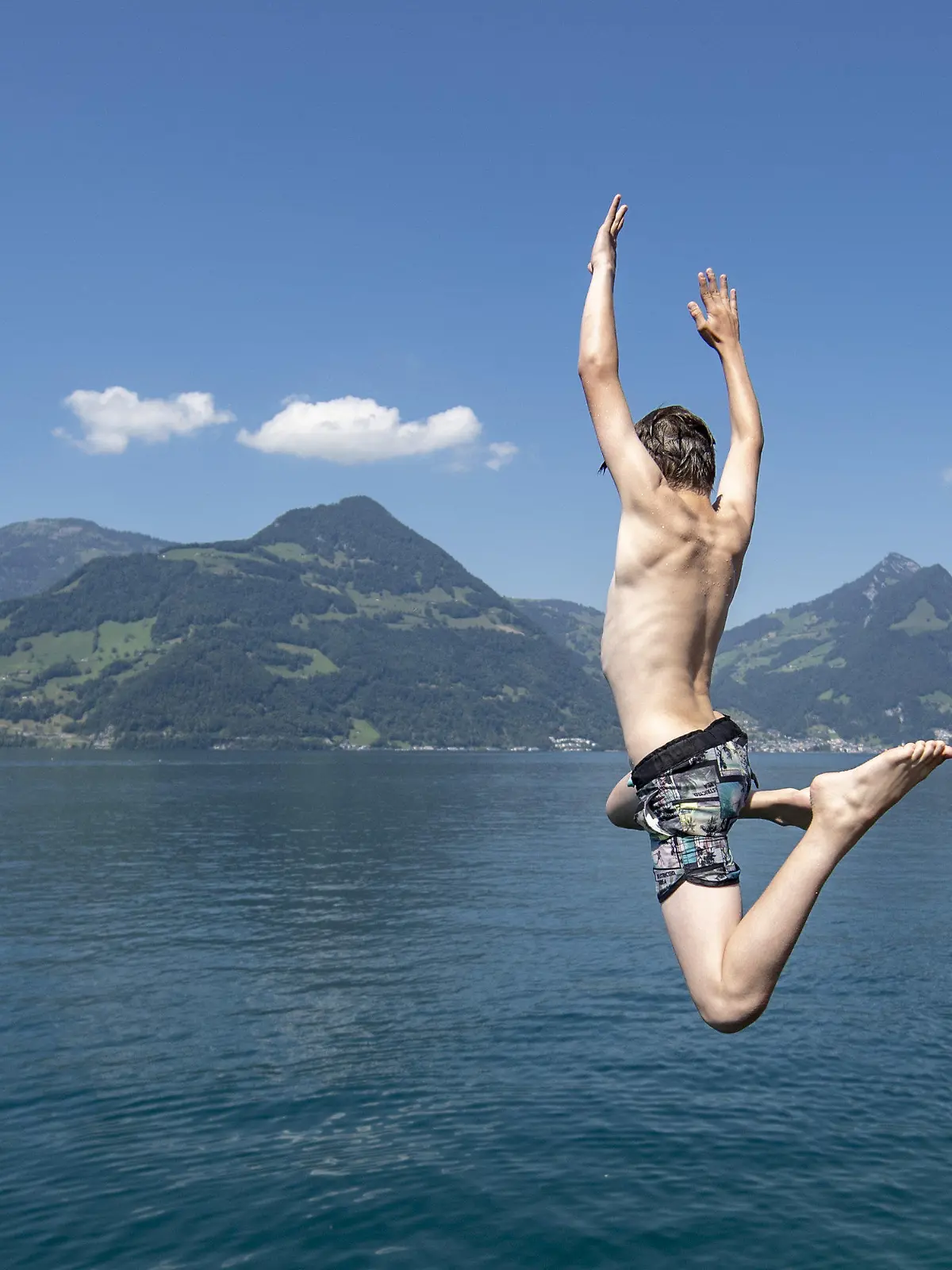 24.06.2020, Schweiz, Beckenried: Ein Junge springt bei Sonnenschein in den Vierwaldstättersee. Foto: Urs Flueeler/KEYSTONE/dpa +++ dpa-Bildfunk +++