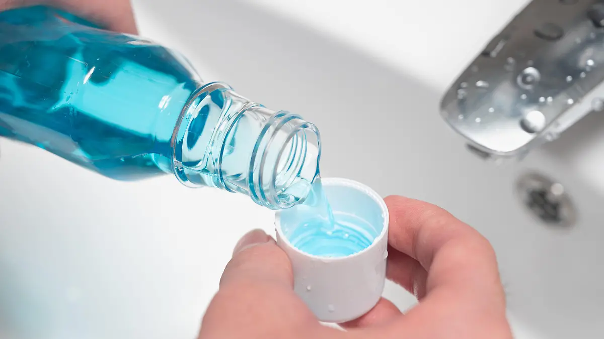 Hand of man Pouring Bottle Of Mouthwash Into Cap.