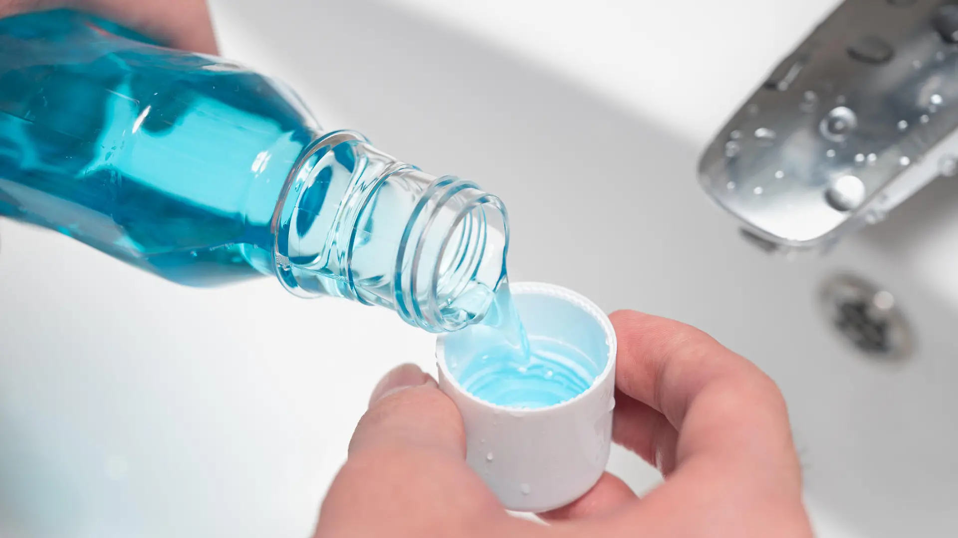 Hand of man Pouring Bottle Of Mouthwash Into Cap.