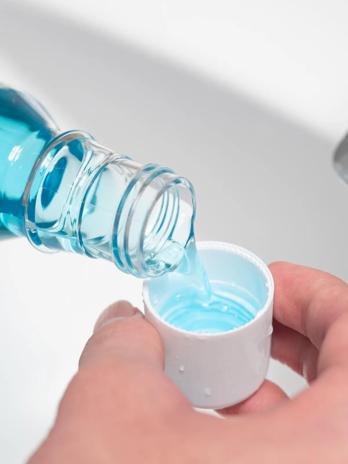 Hand of man Pouring Bottle Of Mouthwash Into Cap.