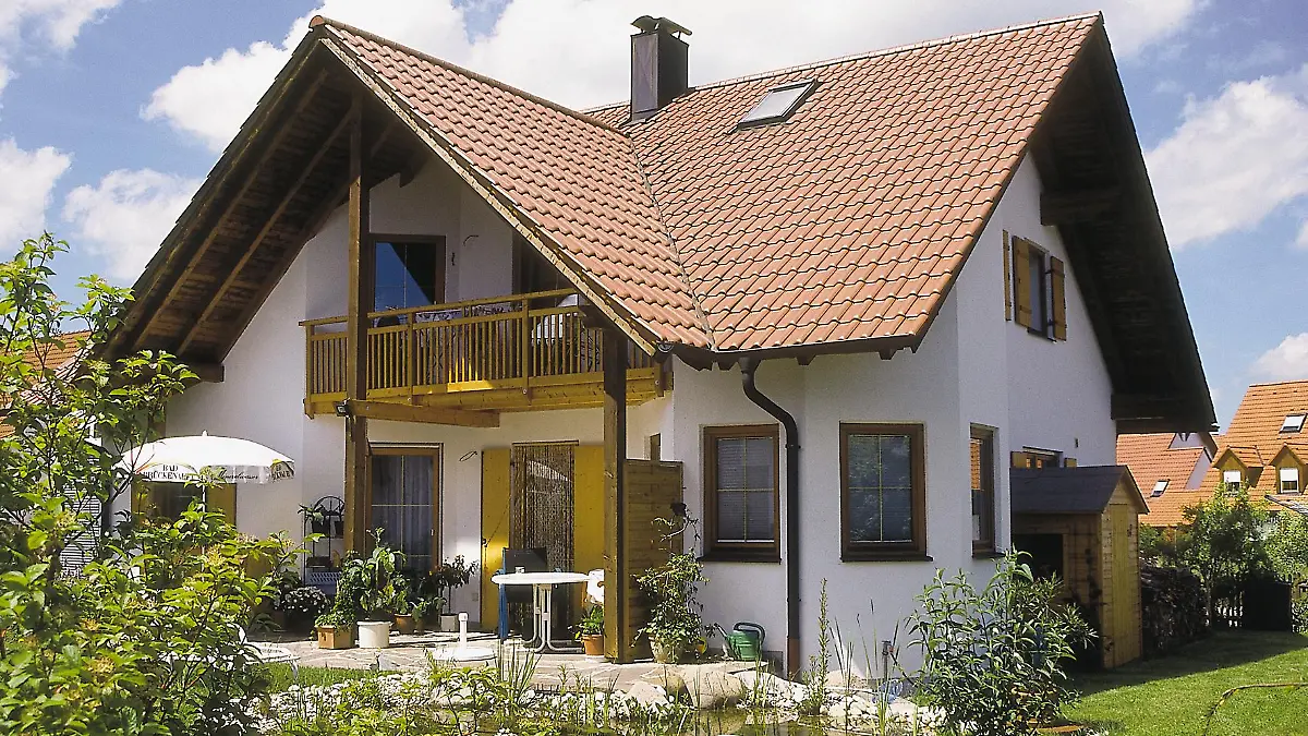Ein Einfamilienhaus mit Terrasse und Teich.