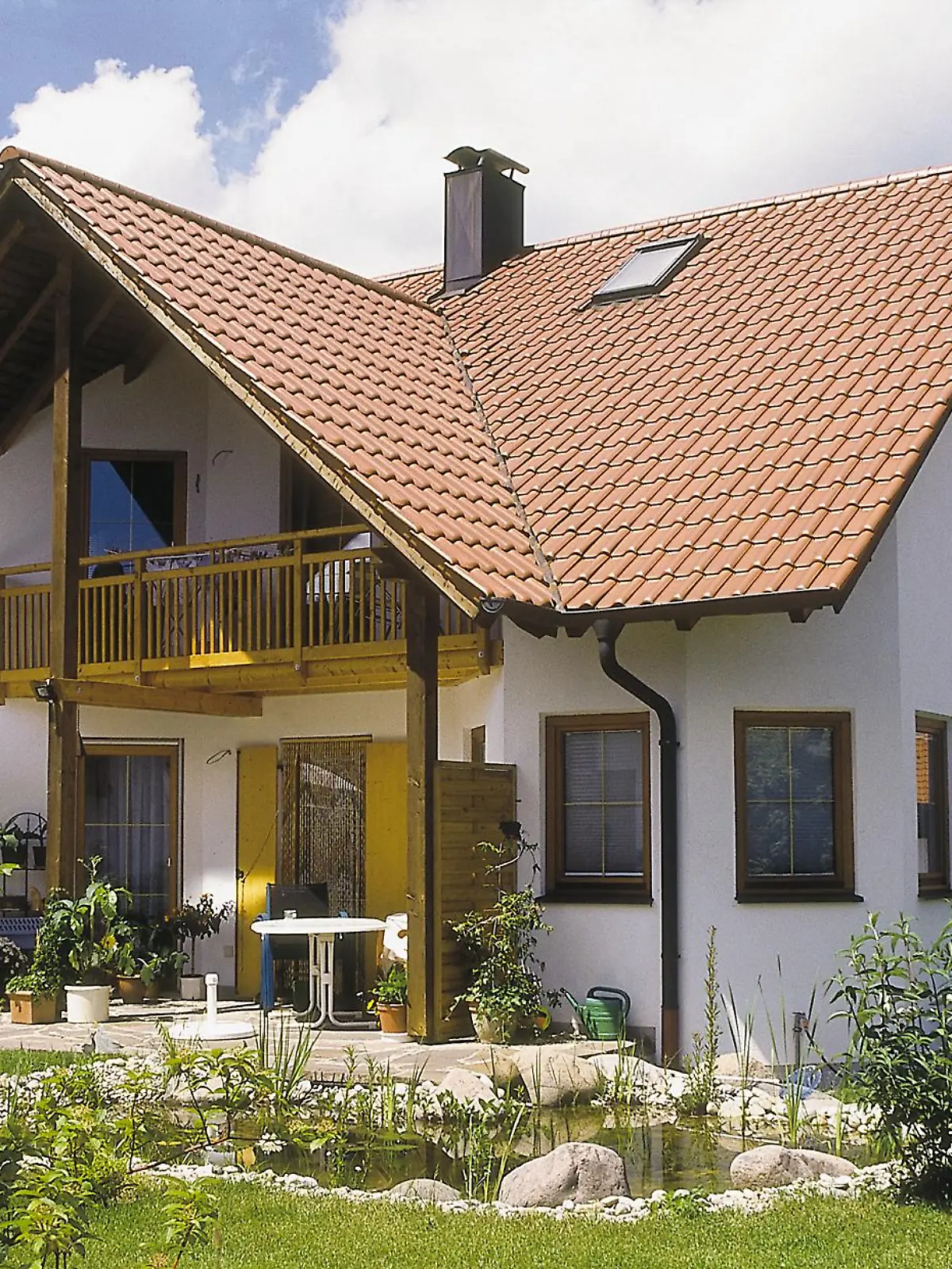 Ein Einfamilienhaus mit Terrasse und Teich.