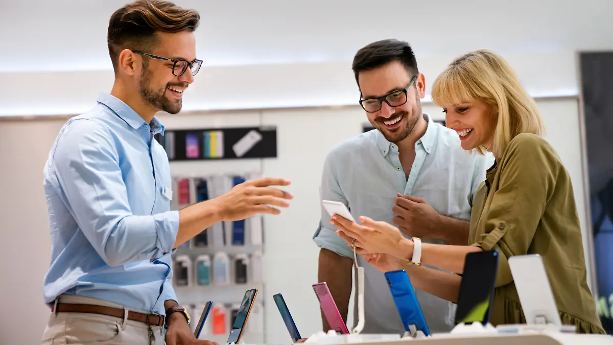Portrait of salesman helping to couple to buy a new digital device in tech shop. Technology people concept