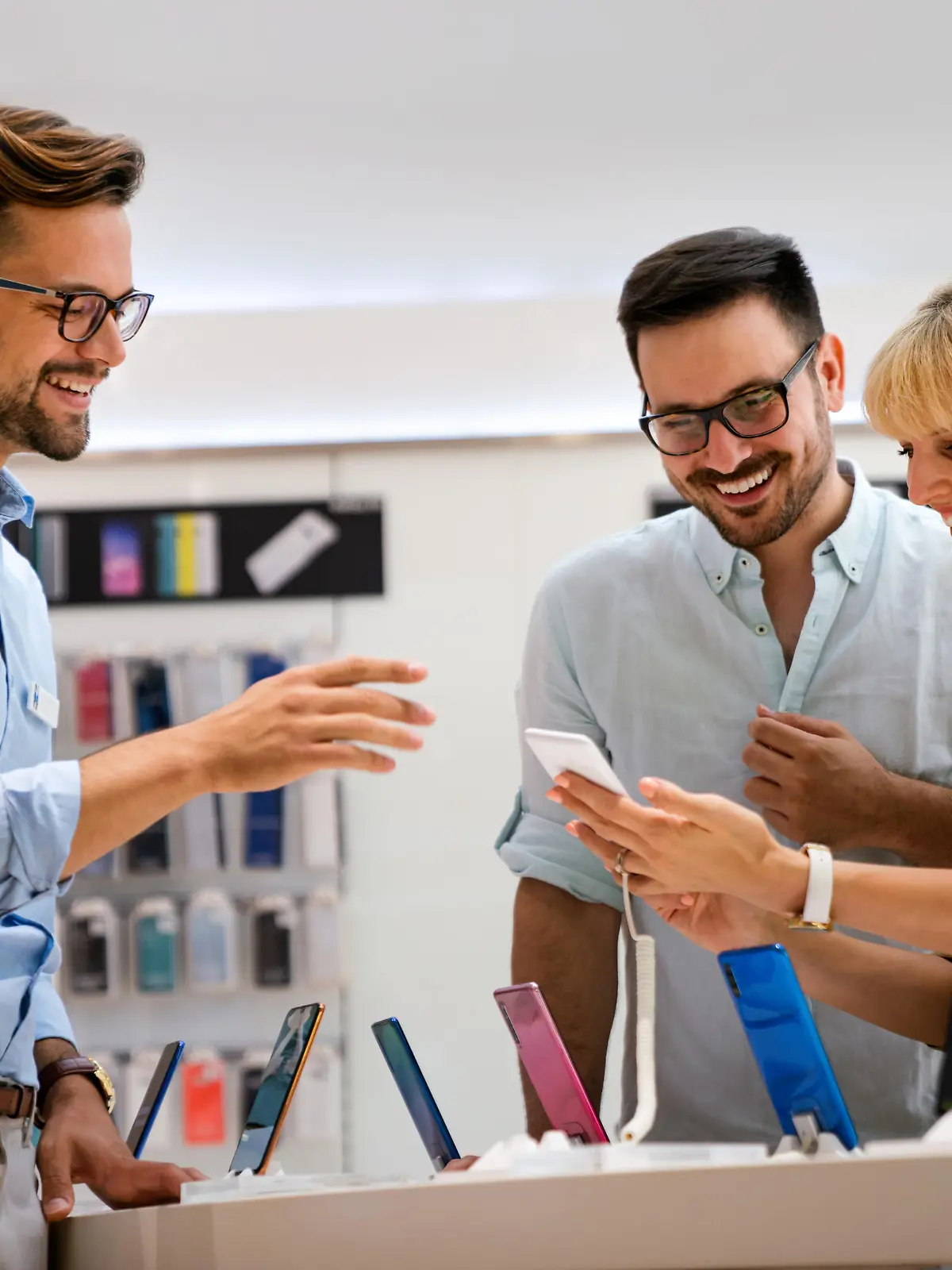 Portrait of salesman helping to couple to buy a new digital device in tech shop. Technology people concept