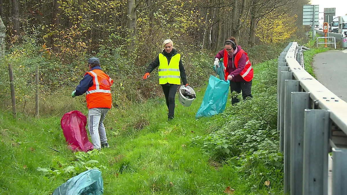 Helferinnen und Helfer packen Abfall in die Mülltüten.