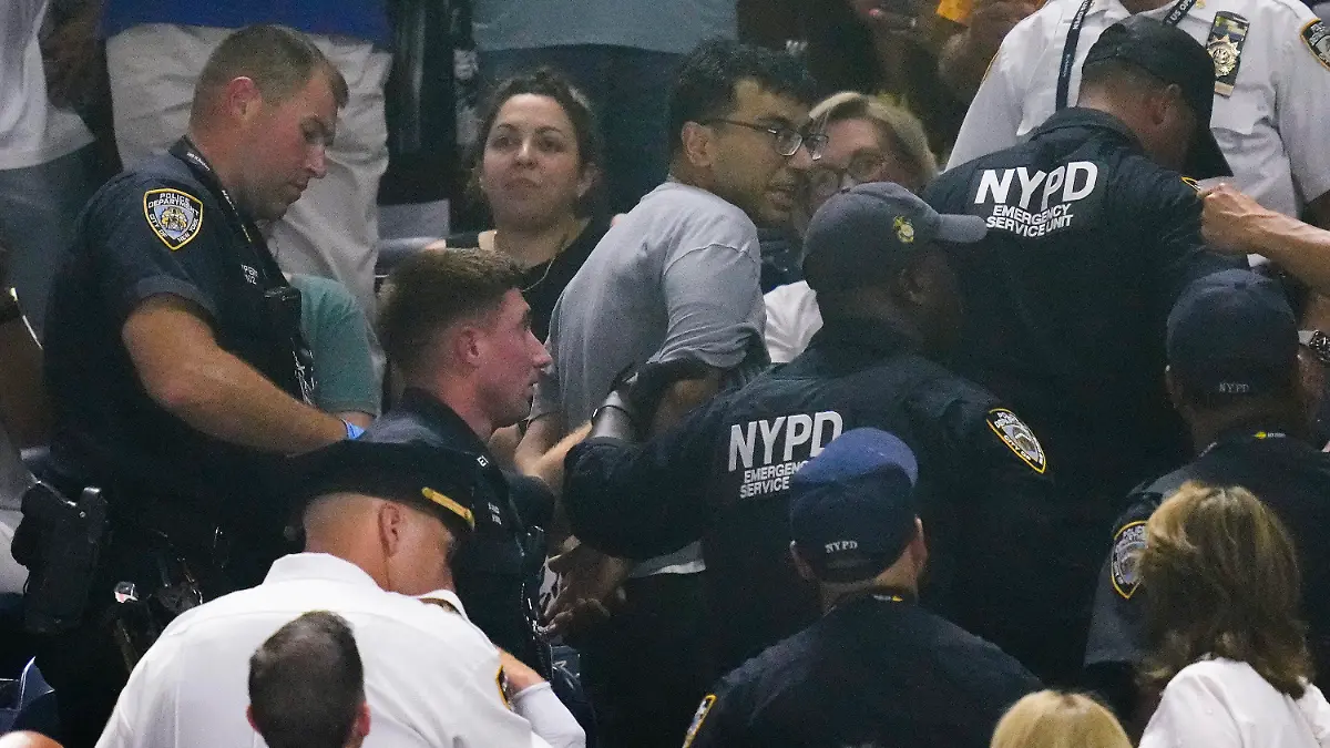 New York police officers escort a protester out of the crowd after a disruption in play between Coco Gauff, of the United States, and Karolina Muchova, of the Czech Republic, during the women's singles semifinals of the U.S. Open tennis championships, Thursday, Sept. 7, 2023, in New York. (AP Photo/Charles Krupa)