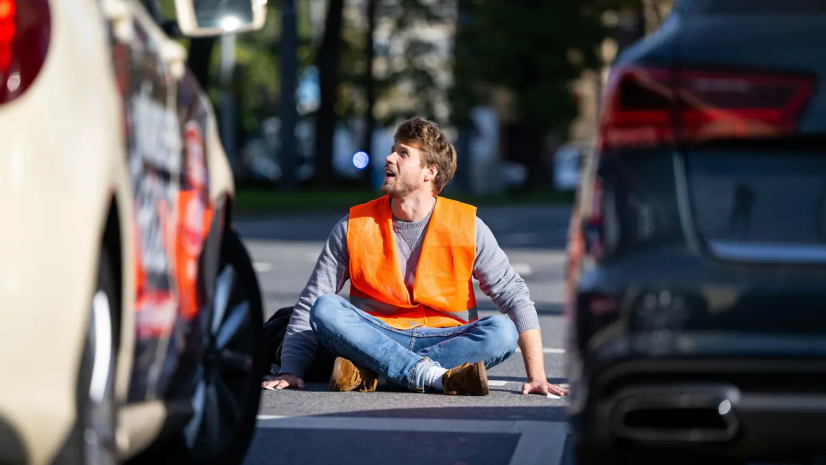 dpatopbilder - 03.11.2022, Bayern, München: Ein Klimaaktivist sitzt am Karlsplatz in der Münchner Innenstadt auf der Fahrbahn und blockiert die Straße. Foto: Lennart Preiss/dpa +++ dpa-Bildfunk +++
