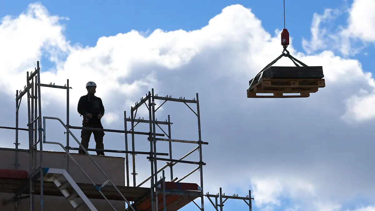 ARCHIV - 05.03.2021, Brandenburg, Potsdam: Ein Arbeiter dirigiert auf einer Baustelle einen Kran. (zu dpa: Bauminister für Förderungen nicht nur für sozialen Wohnungsbau) Foto: Soeren Stache/dpa-Zentralbild/dpa +++ dpa-Bildfunk +++
