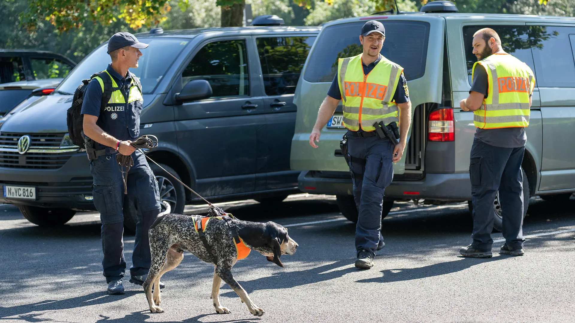 09.09.2023, Bayern, Lohr Am Main: Mit einem Spürhund durchsuchen Polizeibeamte das Gebiet am Schulzentrum in Lohr am Main. Tags zuvor war hier ein toter Jugendlicher gefunden worden. Foto: Pia Bayer/dpa +++ dpa-Bildfunk +++