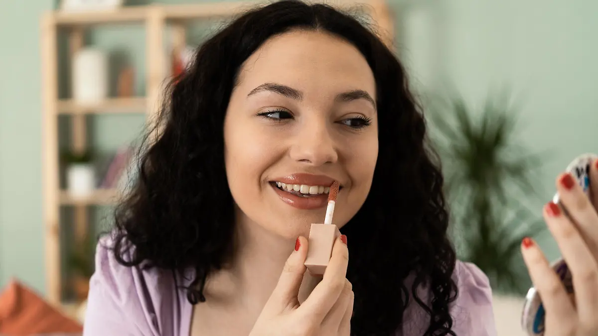 Portrait of a beautiful, young woman putting makeup on her face