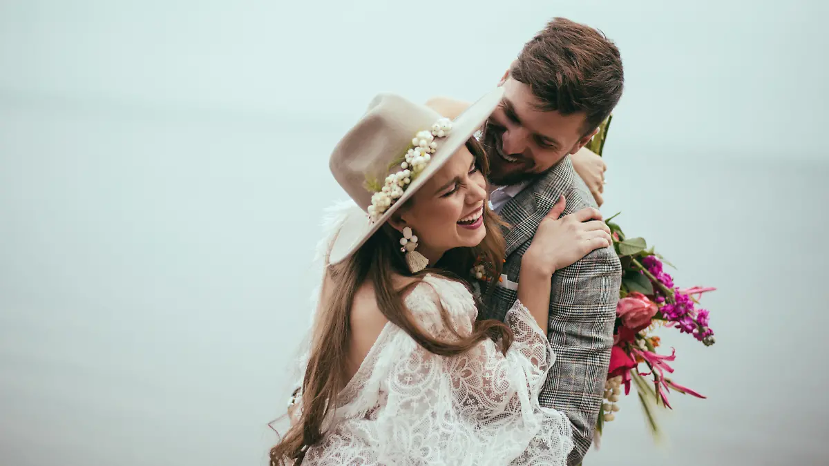 beautiful happy bride and groom in boho style laughing at lake