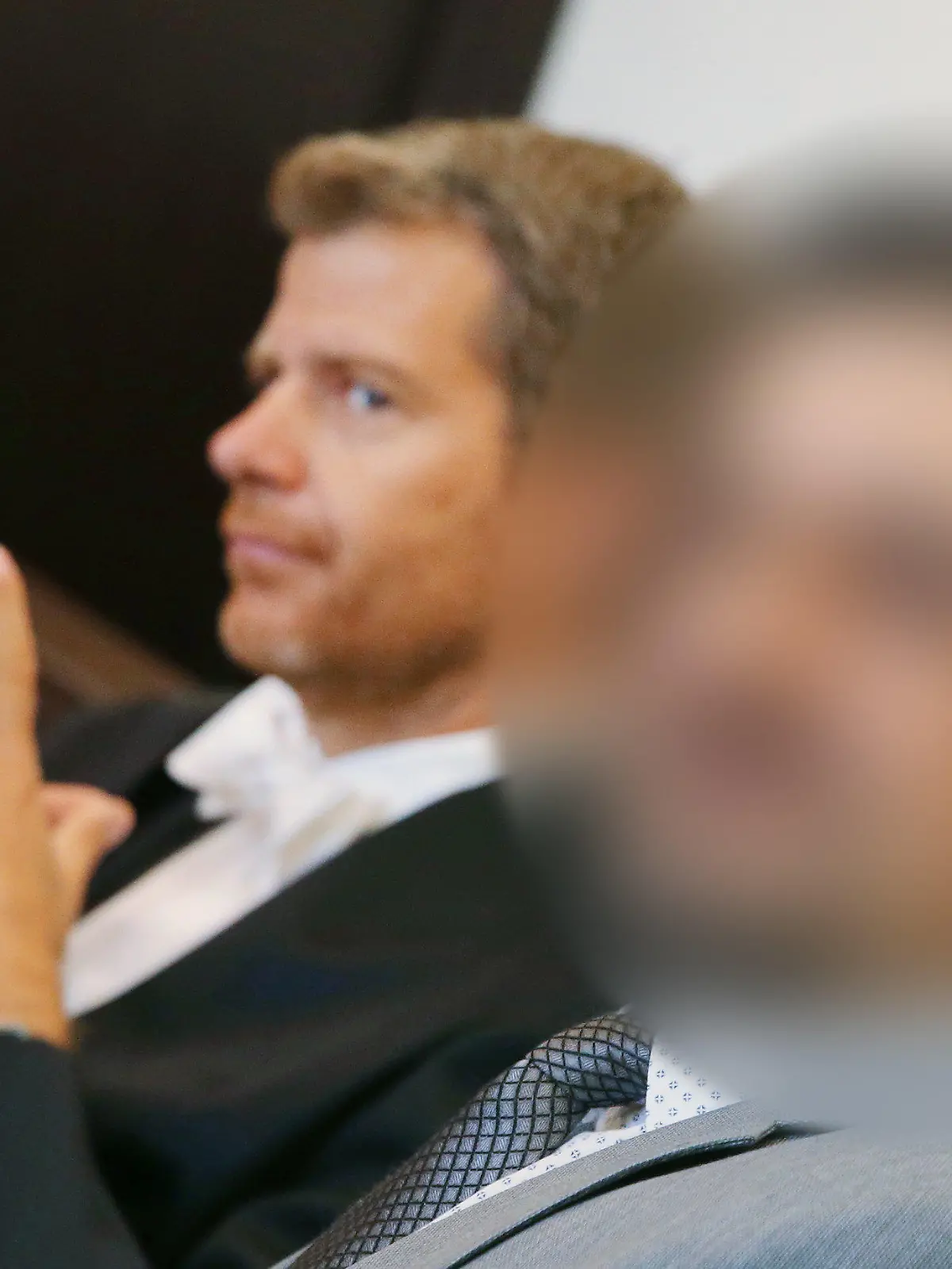 02.08.2019, Nordrhein-Westfalen, Düsseldorf: Anwalt Robert W. Kubach (l) und der Angeklagte sitzen zu Beginn des Prozesses im Gerichtssaal. Der Düsseldorfer Arzt, gegen den nach einer Po-Vergrößerung wegen fahrlässiger Tötung ermittelt wird, muss sich am 2. August 2019 in einer anderen Sache vor Gericht verantworten: Der 47-Jährige hat sich laut Anklage auf seiner Praxis-Homepage und in sozialen Netzwerken als «Dr. med.» ausgegeben, obwohl er nicht promoviert hat und daher keinen Doktortitel besitzt. Foto: David Young/dpa - ACHTUNG: Der Angeklagte wurde aus rechtlichen Gründen gepixelt +++ dpa-Bildfunk +++