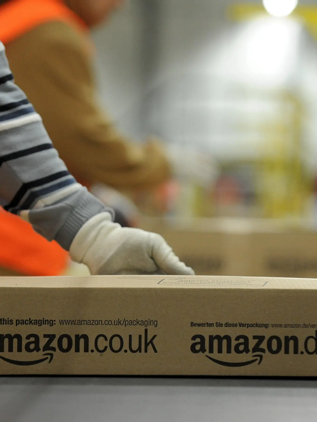 ARCHIV - Ein Mitarbeiter der Versandabteilung des Amazon Logistikzentrums in Pforzheim (Baden-Württemberg) legt am 11.12.2012 ein fertig verpacktes Paket auf ein Fließband. Der Kölner Enthüllungsjournalist Wallraff hat die Arbeitsbedingungen bei dem in die Kritik geratenen Internet-Versandhändler Amazon angeprangert. Foto: Jan-Philipp Strobel/dpa (zu dpa "Wallraff: «Grausamste» Arbeitsbedingungen bei Amazon" vom 18.02.2013) +++(c) dpa - Bildfunk+++