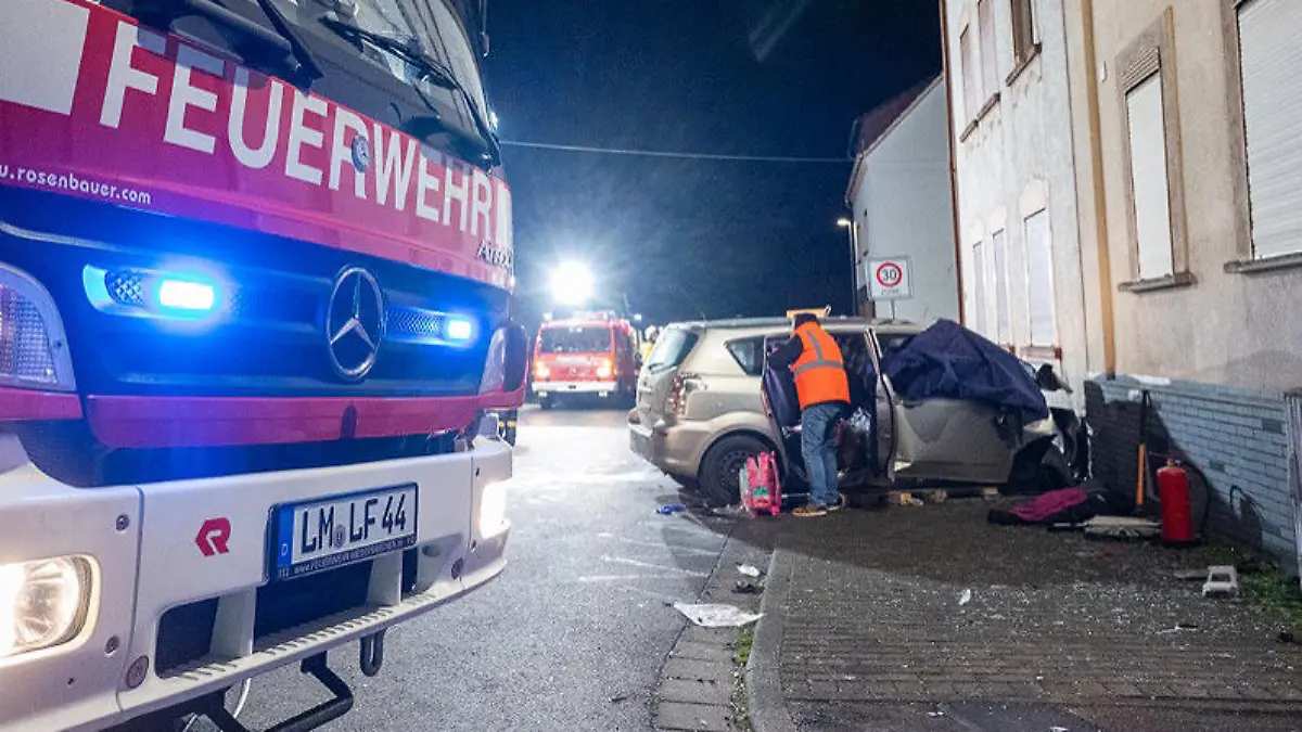 25.11.2022, Hessen, Brechen: Fahrzeuge der Feuerwehr sind nach einem Unfall im Einsatz. Eine 32 Jahre alte Mutter ist in Brechen-Werschau (Landkreis Limburg-Weilburg) bei dem Unfall ums Leben gekommen, als der Wagen ihrer Familie gegen eine Hauswand prallte. Ihre Kinder im Alter von zwölf, acht und einem Jahr sowie der 34-jährige Vater wurden schwer verletzt, wie die Polizei mitteilte. Foto: Keutz TV-NEWS/dpa - ACHTUNG: Bildteile wurden aus Gründen der Pietät gepixelt +++ dpa-Bildfunk +++