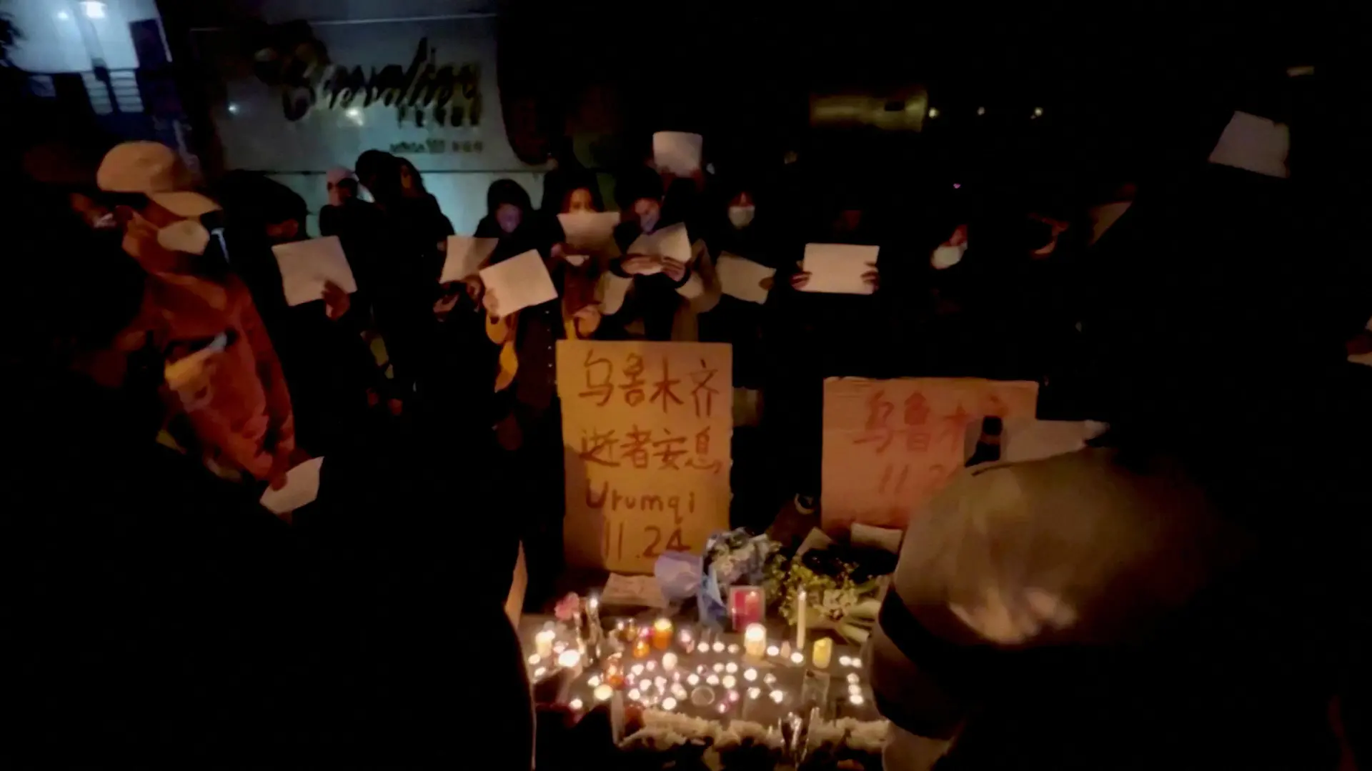 People hold signs and light candles during a vigil held for the victims of the Urumqi fire, in Shanghai, China November 26, 2022 in this picture obtained from a social media video. Gao Ming/via REUTERS THIS IMAGE HAS BEEN SUPPLIED BY A THIRD PARTY. MANDATORY CREDIT. NO RESALES. NO ARCHIVES.