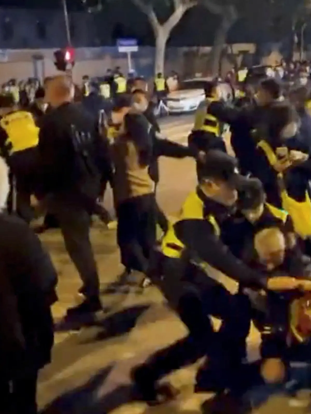 Police officers detain people during a protest against coronavirus disease (COVID-19) curbs at the site of a candlelight vigil for victims of the Urumqi fire, in Shanghai, China in this screengrab obtained from a video released on November 27, 2022. Video obtained by Reuters/via REUTERS  THIS IMAGE HAS BEEN SUPPLIED BY A THIRD PARTY. NO RESALES. NO ARCHIVES.