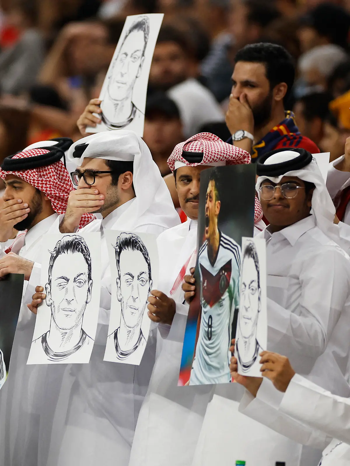 Soccer Football - FIFA World Cup Qatar 2022 - Group E - Spain v Germany - Al Bayt Stadium, Al Khor, Qatar - November 27, 2022 Fans hold up signs displaying former Germany player Mesut Ozil in the stands REUTERS/John Sibley