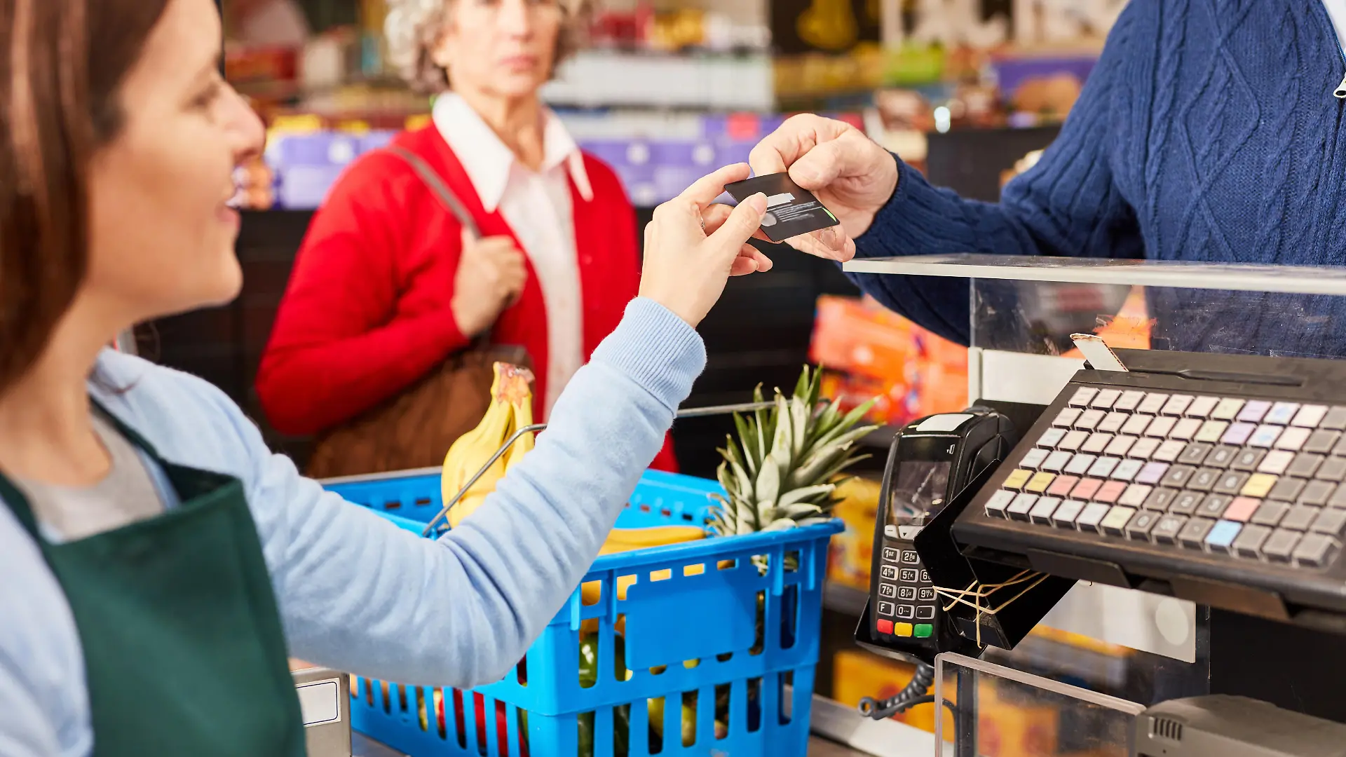 Kunde bezahlt mit Kreditkarte oder Kundenkarte an der Kasse im Supermarkt