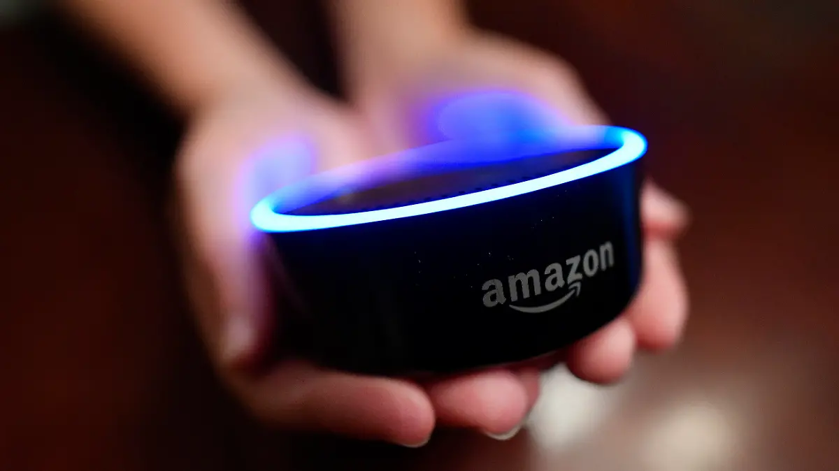 FILE - In this Aug. 16, 2018, file photo a child holds his Amazon Echo Dot in Kennesaw, Ga. From what you buy online, to how you remember tasks, to when you monitor your doorstep, Amazon is seemingly everywhere. And it appears the company doesn’t want to halt its reach anytime soon. In recent weeks, Amazon has said it will spend billions of dollars in two gigantic acquisitions that, if approved, will broaden its ever growing presence in the lives of consumers. (AP Photo/Mike Stewart, File)