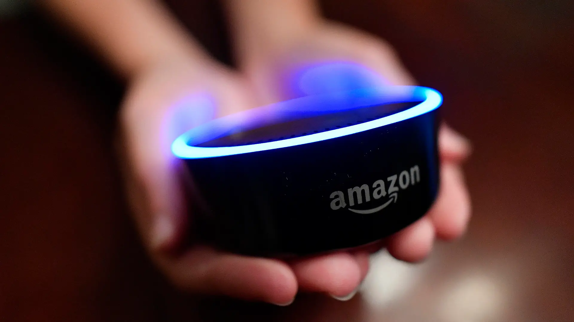 FILE - In this Aug. 16, 2018, file photo a child holds his Amazon Echo Dot in Kennesaw, Ga. From what you buy online, to how you remember tasks, to when you monitor your doorstep, Amazon is seemingly everywhere. And it appears the company doesn’t want to halt its reach anytime soon. In recent weeks, Amazon has said it will spend billions of dollars in two gigantic acquisitions that, if approved, will broaden its ever growing presence in the lives of consumers. (AP Photo/Mike Stewart, File)