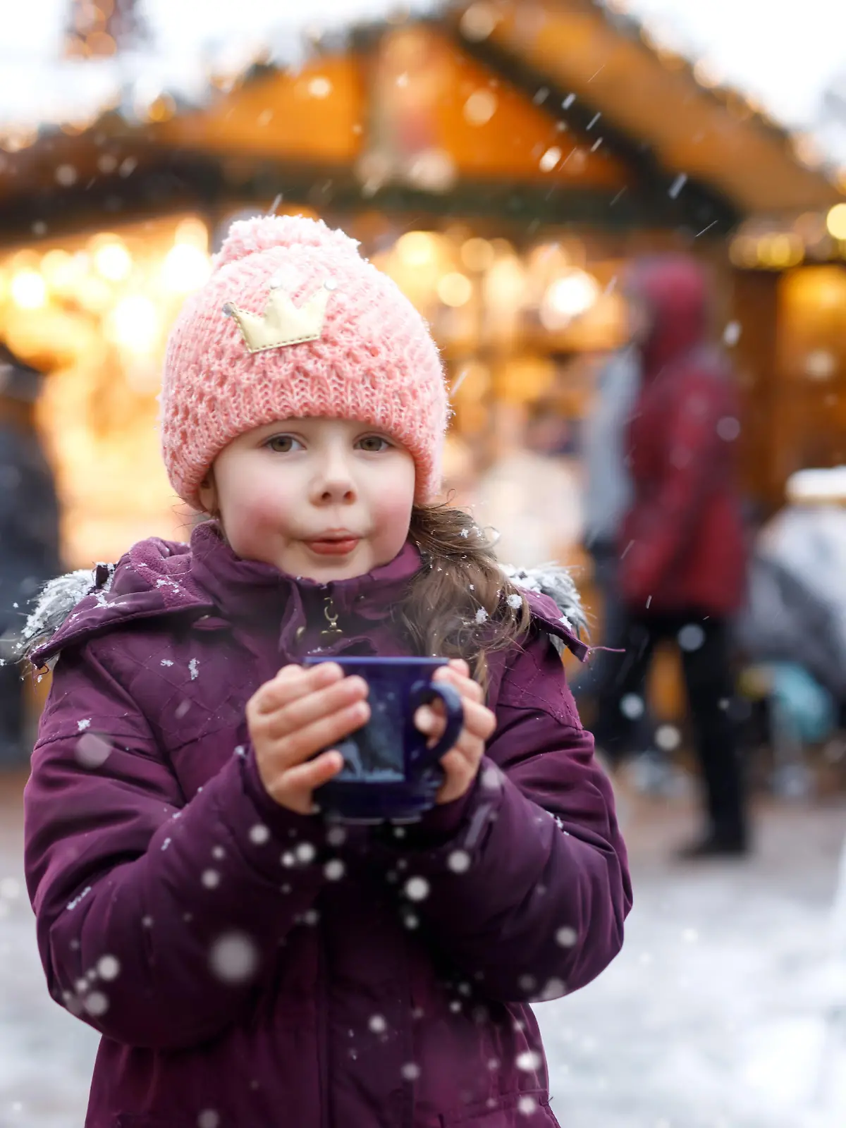 Little cute kid girl with cup of steaming hot chocolate or children punch. Happy child on Christmas market in Germany. Traditional leisure for families on xmas