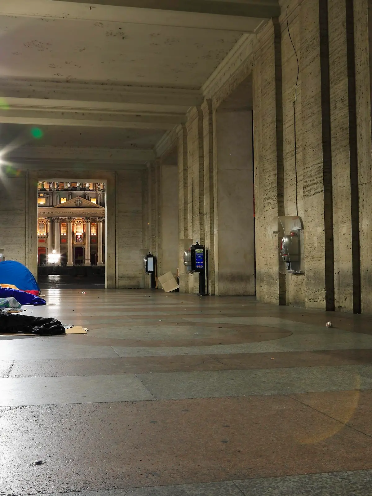 Obdachlose schlafen in der Vorhalle der Opera Romana Pellegrinaggi unweit des Petersplatzes. Im Bildhintergrund sind ein Teil des Petersplatzes sowie ein Teil des Petersdomes zu sehen. Ueber dem Hauptportal des Petersdomes ist noch das Bild von Mutter Teresa von Kalkutta zu erkennen, die zwei Tage zuvor, am 04. September 2016, durch Papst Franziskus auf dem Petersplatz Heilig gesprochen wurde.
