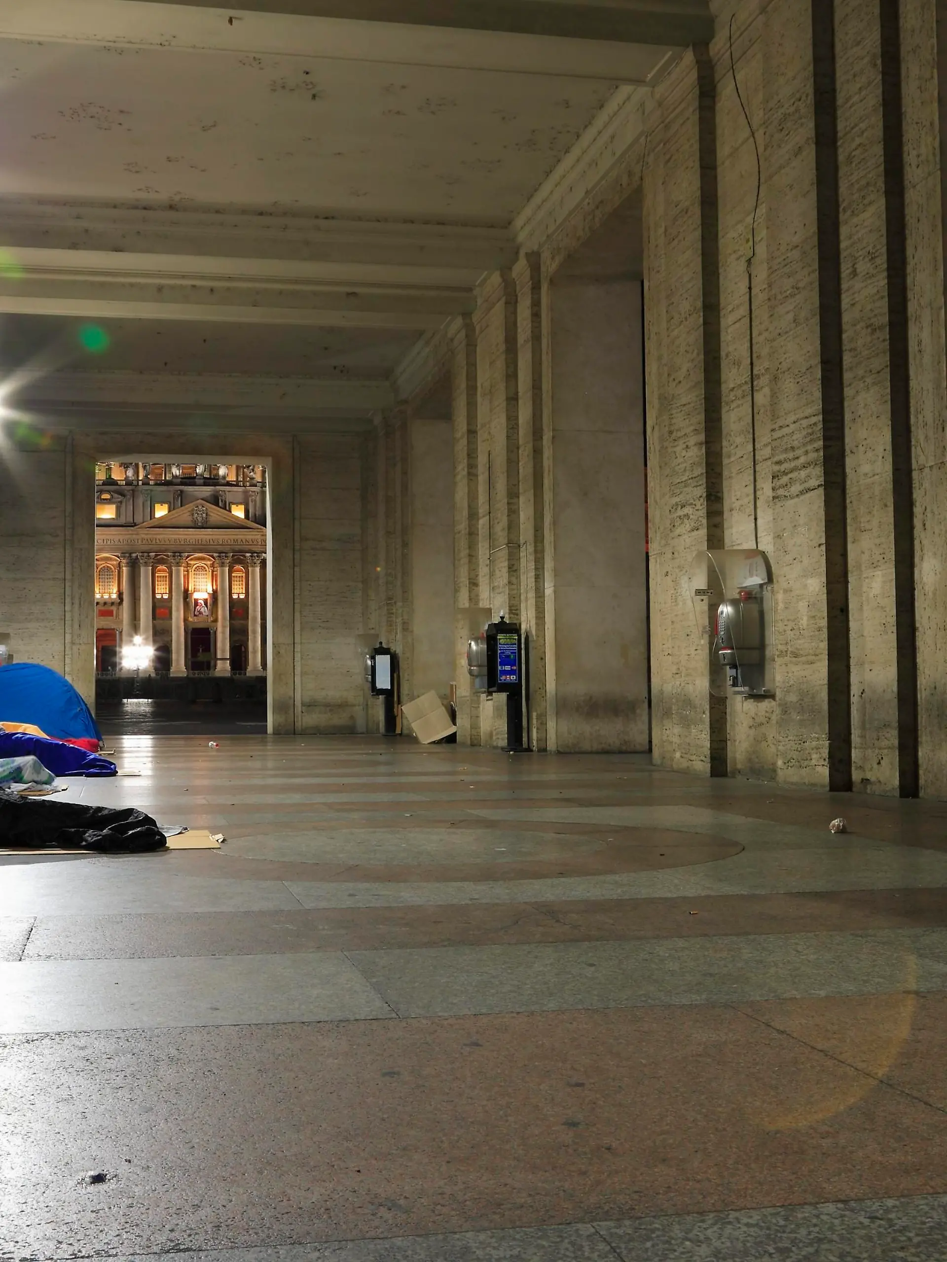 Obdachlose schlafen in der Vorhalle der Opera Romana Pellegrinaggi unweit des Petersplatzes. Im Bildhintergrund sind ein Teil des Petersplatzes sowie ein Teil des Petersdomes zu sehen. Ueber dem Hauptportal des Petersdomes ist noch das Bild von Mutter Teresa von Kalkutta zu erkennen, die zwei Tage zuvor, am 04. September 2016, durch Papst Franziskus auf dem Petersplatz Heilig gesprochen wurde.