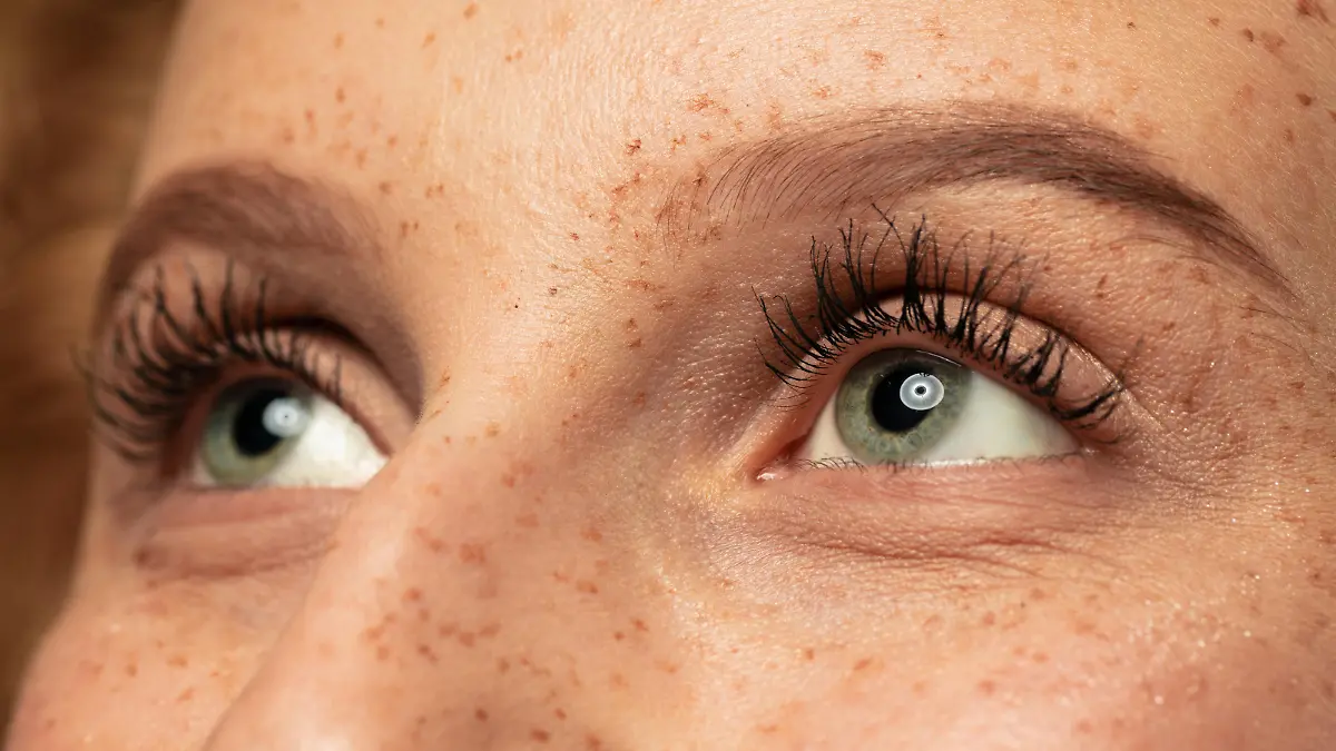 Frau mit langen Wimpern guckt nach oben.