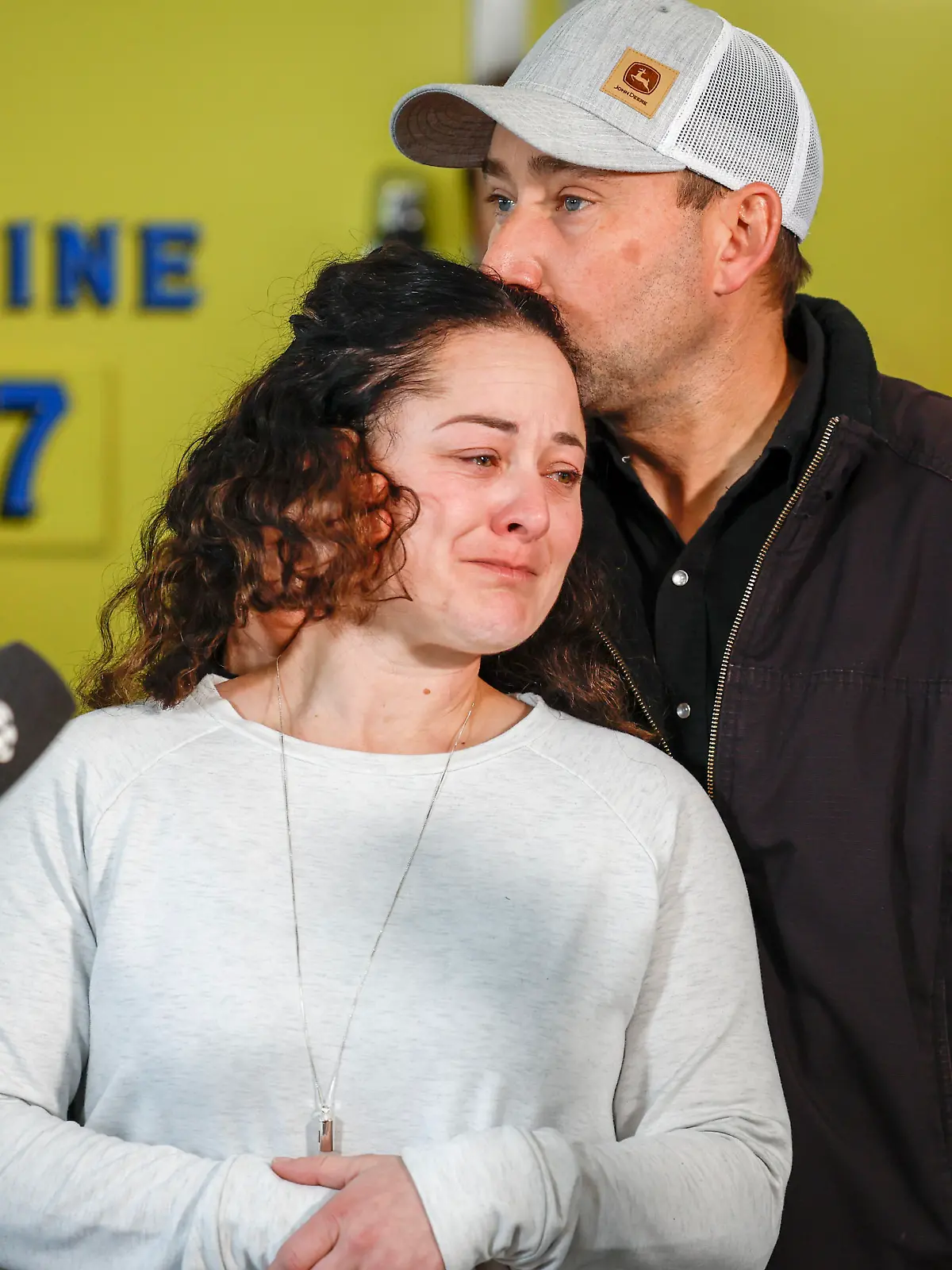Paramedic Jayme Erickson, center, who was called to a crash last week and didn't know she was trying to save her own daughter because the injuries were too severe, is comforted by her husband Sean Erickson, as she speaks to the media in Airdrie, Alberta, Tuesday, Nov. 22, 2022. (Jeff McIntosh/The Canadian Press via AP)