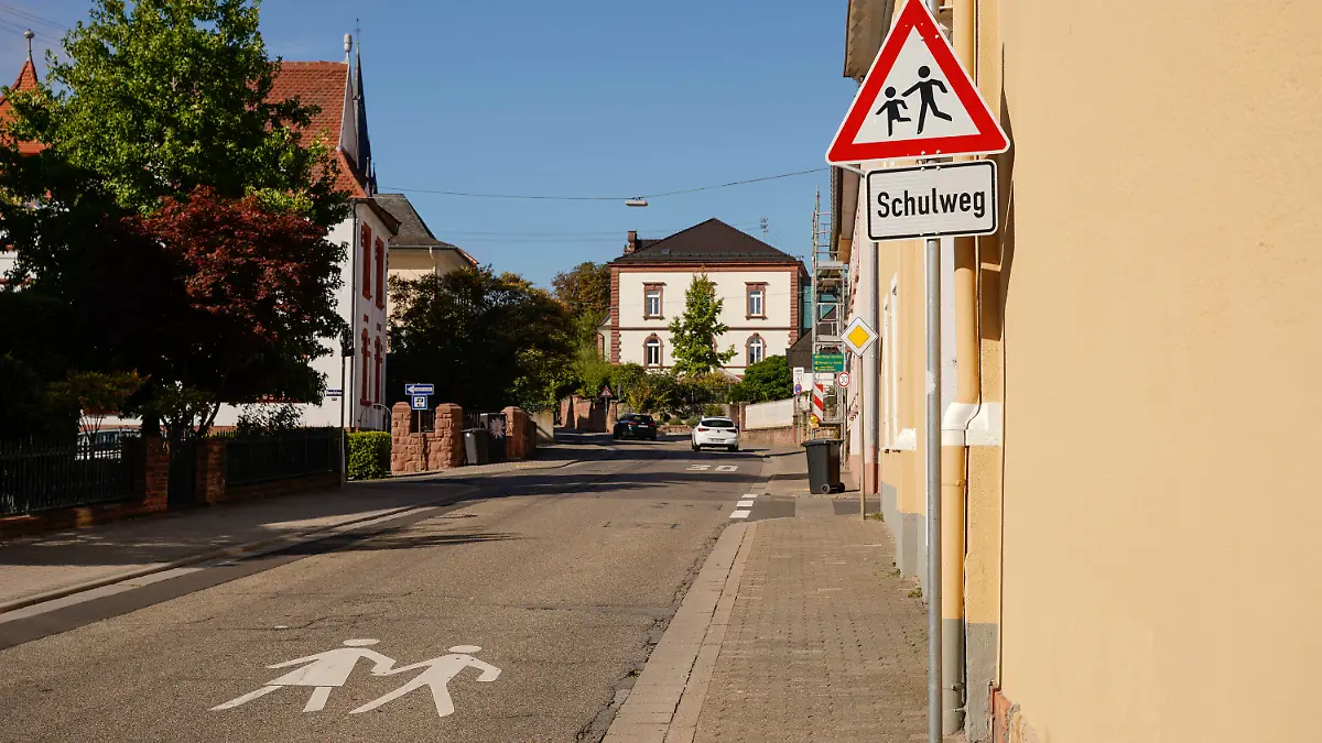 14.09.2023, Rheinland-Pfalz, Edenkoben: Ein Warnschild und ein Schild mit der Aufschrift ·Schulweg· stehen am Rand der Luitpoldstraße. In dieser Straße soll ein verurteilter Sexualstraftäter eine Zehnjährige auf dem Schulweg in sein Auto gezerrt, entführt und mutmaßlich missbraucht haben. Foto: Uwe Anspach/dpa +++ dpa-Bildfunk +++