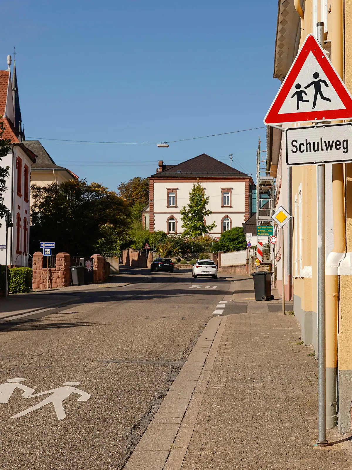 14.09.2023, Rheinland-Pfalz, Edenkoben: Ein Warnschild und ein Schild mit der Aufschrift ·Schulweg· stehen am Rand der Luitpoldstraße. In dieser Straße soll ein verurteilter Sexualstraftäter eine Zehnjährige auf dem Schulweg in sein Auto gezerrt, entführt und mutmaßlich missbraucht haben. Foto: Uwe Anspach/dpa +++ dpa-Bildfunk +++