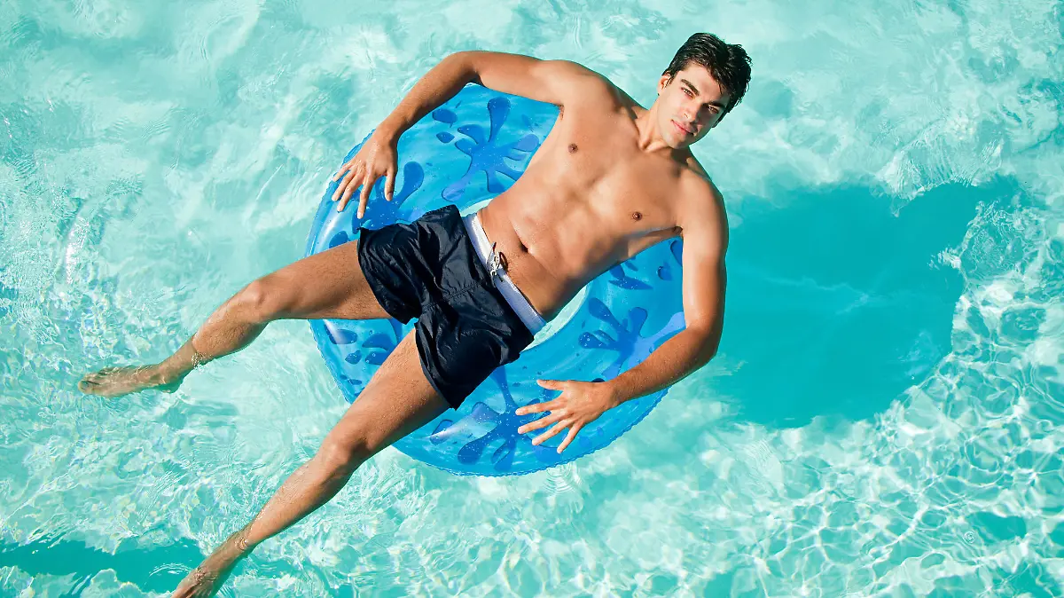 Mann, der auf einem Schwimmring im Pool schwimmt.