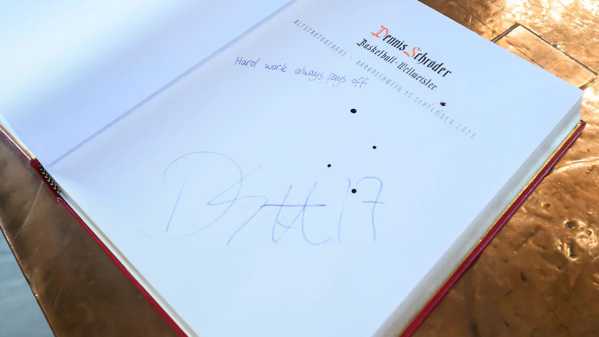 15.09.2023, Niedersachsen, Braunschweig: Blick auf die Seite im goldenen Buch der Stadt Braunschweig, nachdem sich Basketballweltmeister Dennis Schröder mit dem Schriftzug «Hard work always pays off» (dt. «Harte Arbeit zahlt sich immer aus») verewigen durfte. NBA-Basketballspieler Dennis Schröder hat sich ins Goldene Buch der Stadt Braunschweig eingetragen und von tausenden Fans in seiner Heimatstadt feiern lassen. Foto: Julian Stratenschulte/dpa +++ dpa-Bildfunk +++
