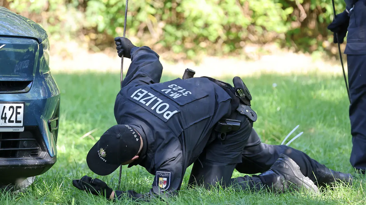 15.09.2023, Mecklenburg-Vorpommern, Pragsdorf: Polizisten durchkämmen den Bereich rund um den Tatort am See und schauen dabei auch unter Autos, wo am Abend des 14.09.2023 der schwer verletzte Sechsjährige gefunden wurde, der später an seinen Verletzungen verstarb. Die Polizei ermittelt wegen Totschlags. Foto: Bernd Wüstneck/dpa +++ dpa-Bildfunk +++