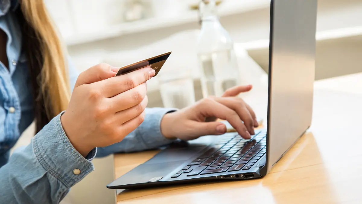 ARCHIV - 01.10.2020, Brandenburg, Wittenberge: ILLUSTRATION - Eine Frau sitzt mit einer Kreditkarte am Laptop. Der drastische Anstieg der Lebenshaltungskosten in Deutschland hat auch das Einkaufsverhalten der Online-Shopper verändert. Die Menschen überlegen sorgfältiger, was sie wirklich brauchen und achten vermehrt auf Sonderangebote.      (zu dpa "Umfrage: Auch beim Online-Shoppen wird gespart") Foto: Christin Klose/dpa +++ dpa-Bildfunk +++