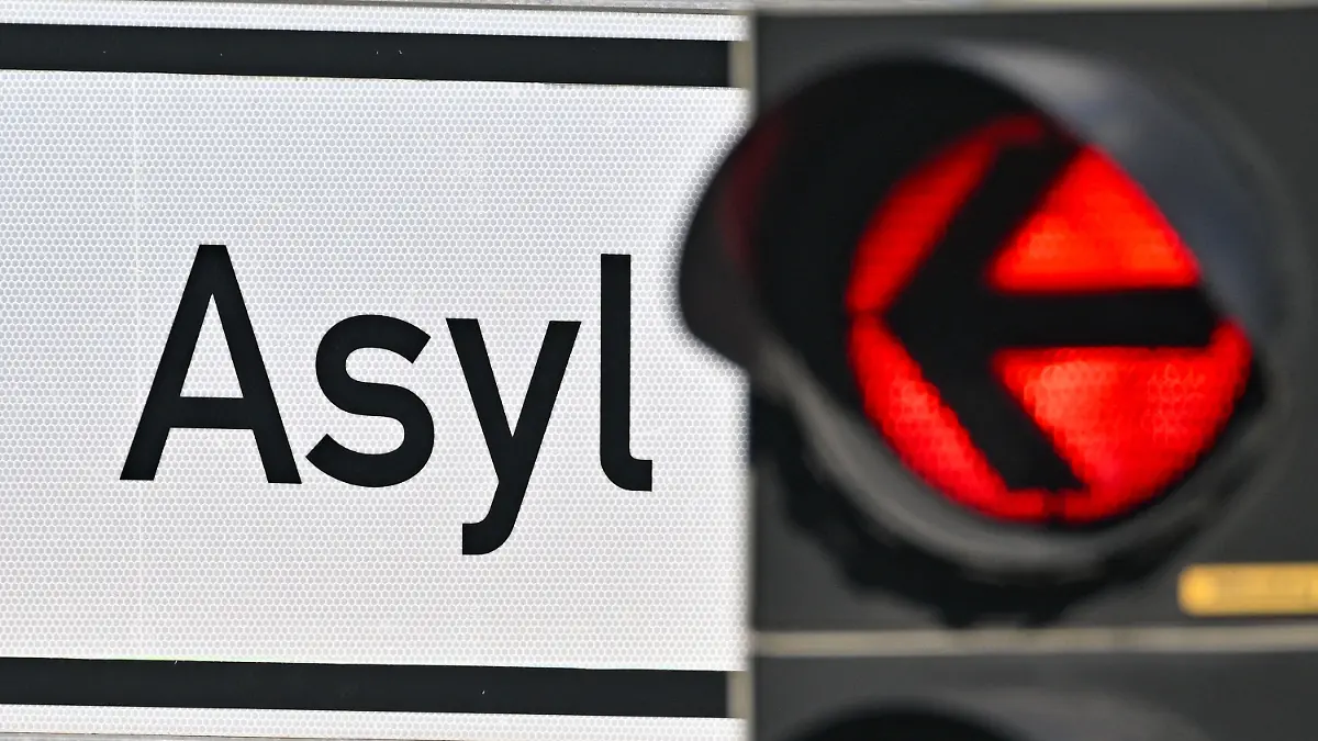 ARCHIV - 06.09.2023, Brandenburg, Eisenhüttenstadt: Eine rote Ampel leuchtet vor dem Wort «Asyl» auf einem Wegweiser zur Erstaufnahme-Einrichtungen (EAE) des Landes Brandenburg in Eisenhüttenstadt. Die Zahl der Asylbewerber in Deutschland dürfte nach Schätzungen des CDU-Politikers Thorsten Frei im laufenden Jahr auf 350 000 steigen. (zu dpa «CDU-Politiker erwartet 350 000 Asylbewerber - «Kontrolle verloren»») Foto: Patrick Pleul/dpa +++ dpa-Bildfunk +++